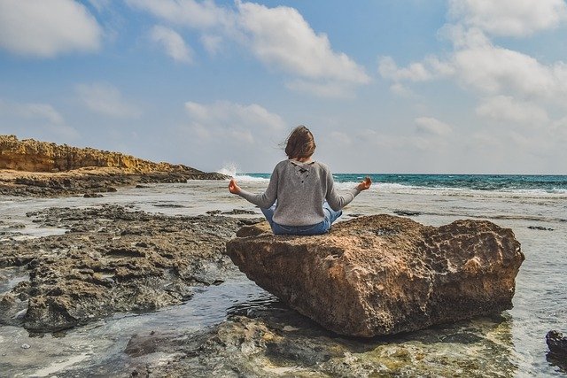 mujer meditando en la orilla del mar
